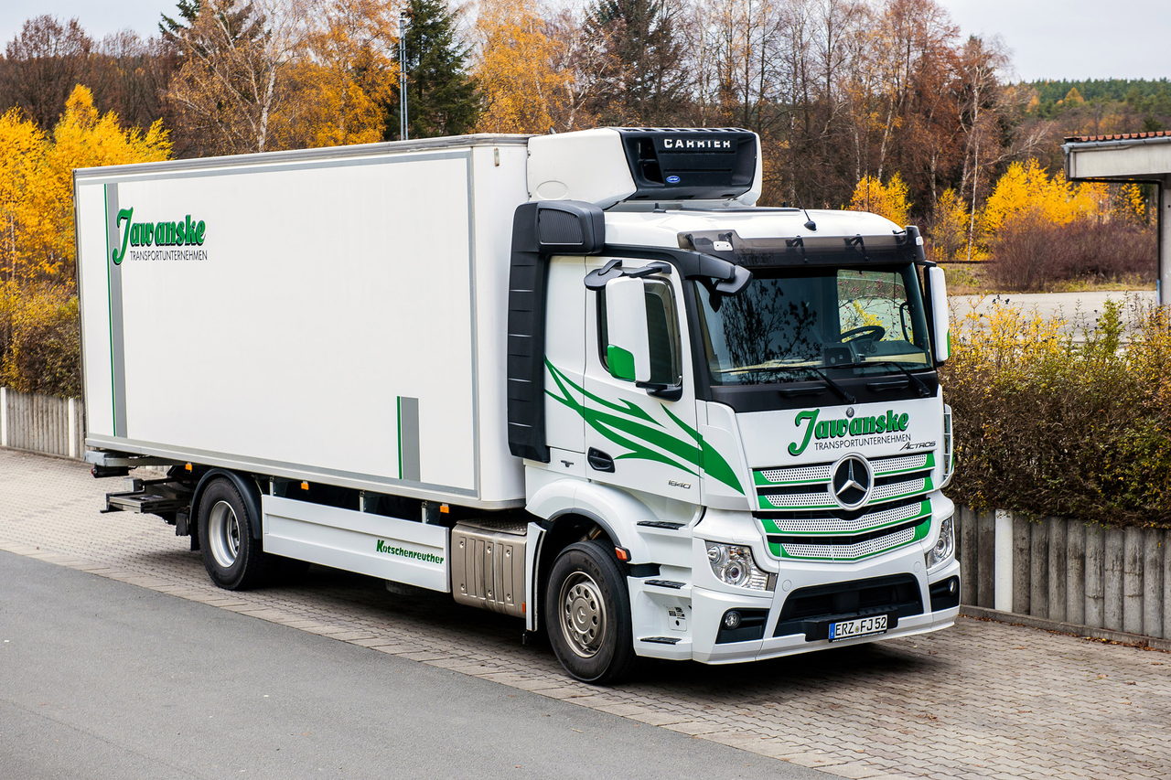 Weißer Mercedes-Benz LKW mit "Juraschek" Aufschrift und grünem Logo parkt auf einem asphaltierten Weg.