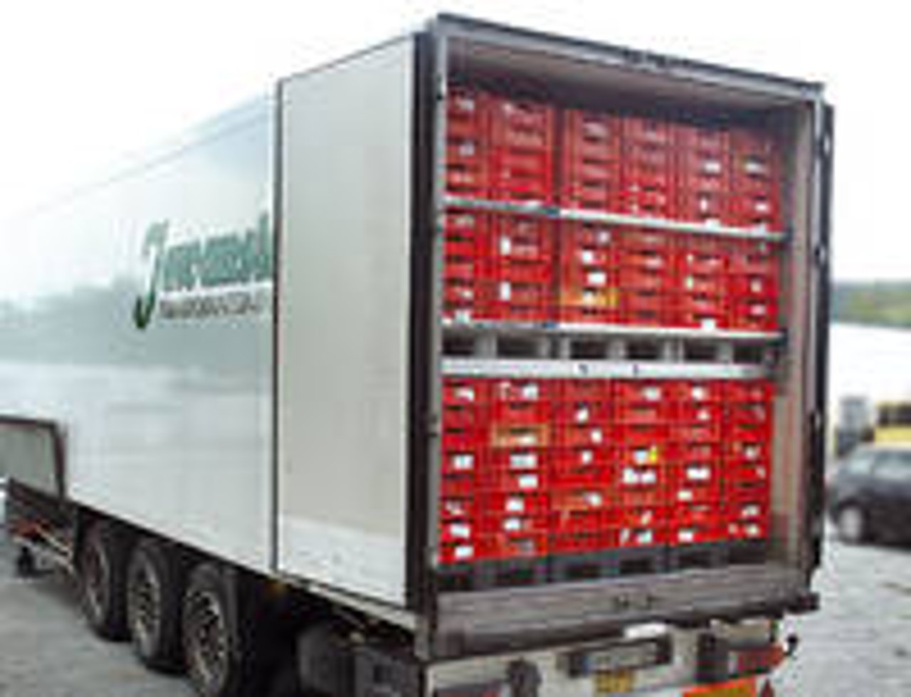 Ein LKW-Anhänger mit offener Hecktür, gefüllt mit roten Kisten auf Paletten.